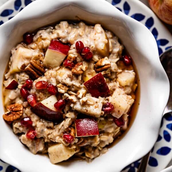 Apple cinnamon oatmeal in a bowl topped with apple oatmeal toppings.