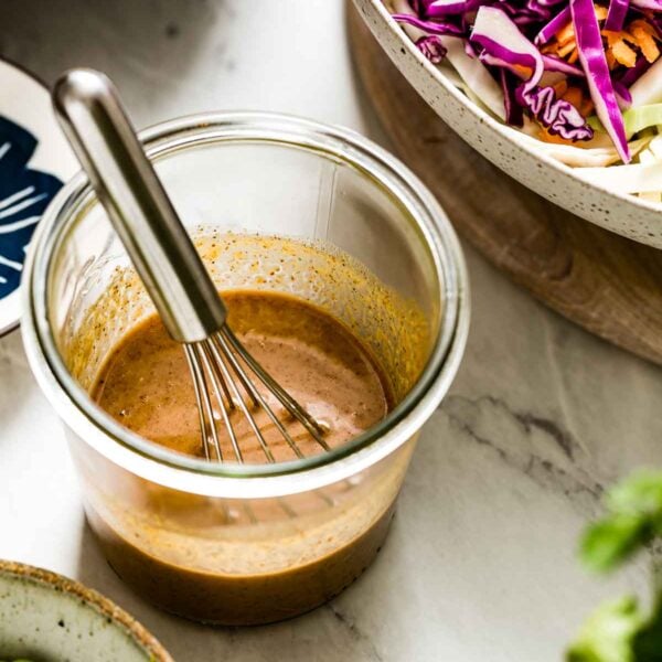 Asian Sesame Ginger Dressing Recipe in a clear jar with a whisk