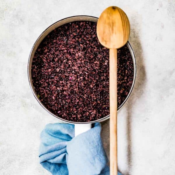 cooked black rice in a saucepan with a wooden spoon on the side