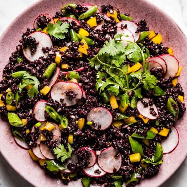 Black rice salad on a pink plate from the top view