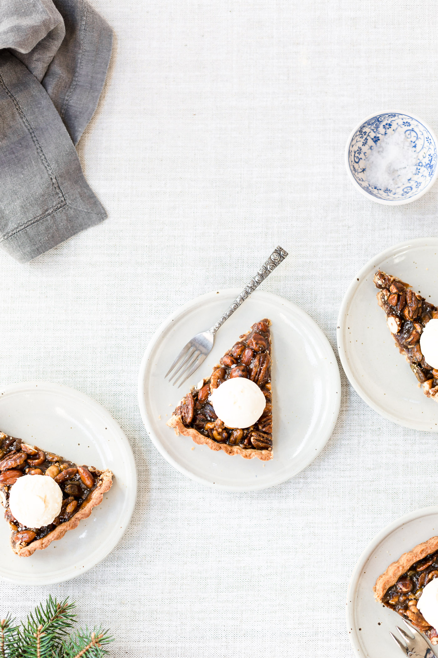 A few slices of caramel nut tart topped off with scoops of vanilla ice cream photographed from the top view.