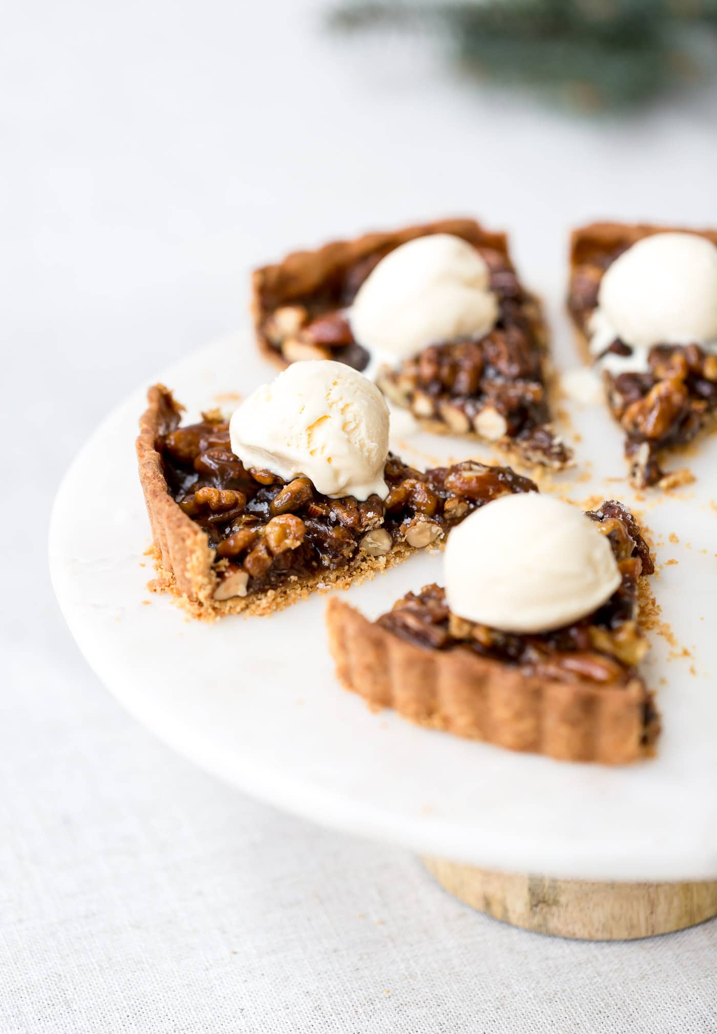 A few slices of caramel nut tart are topped off with a scoop of vanilla ice cream.