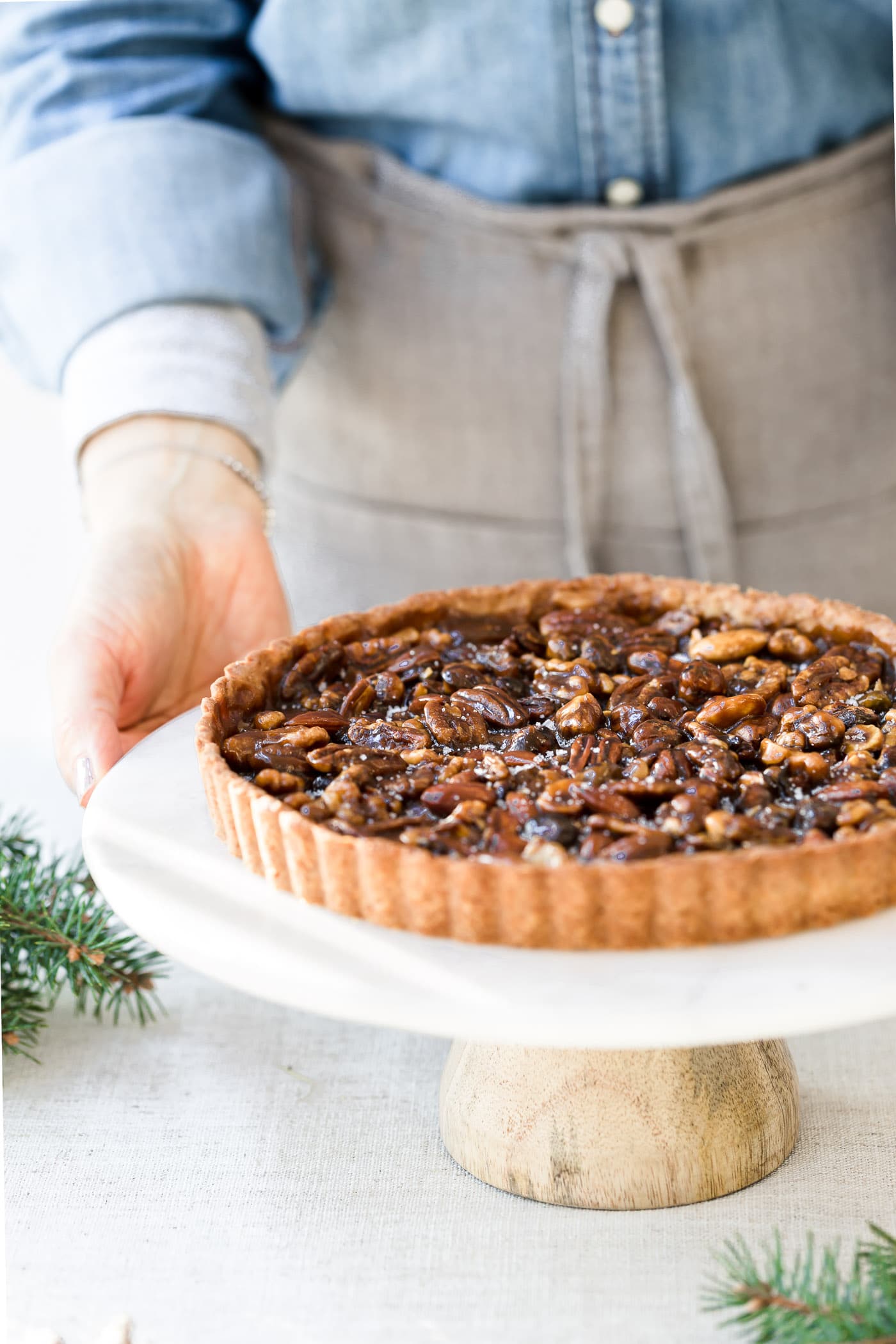 A woman is about to serve a naturally sweetened caramel nut tart.