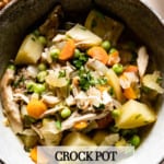 Chicken breast stew in a bowl with potatoes, carrots and peas from the top view.