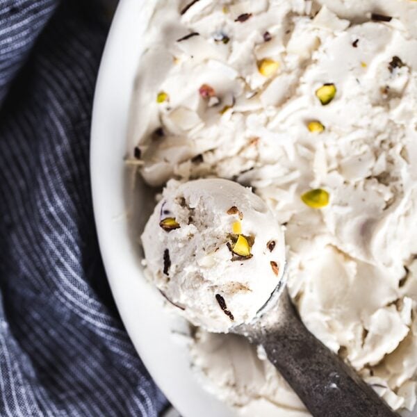 Coconut Cashew Ice Cream in a casserole dish with an ice cream scoop on the side.