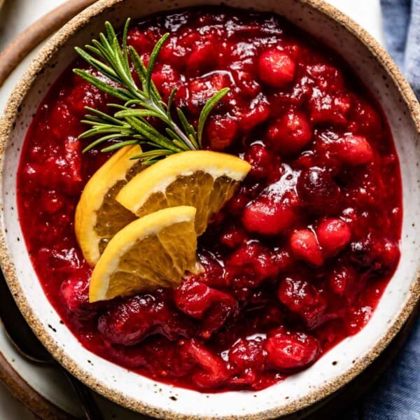 Cranberry sauce in a bowl garnished with orange slices from the top view.