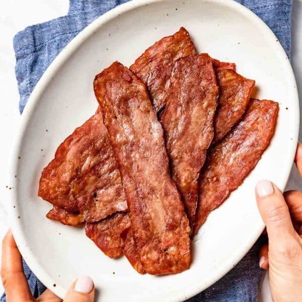 Cooked turkey bacon in a plate served by a person
