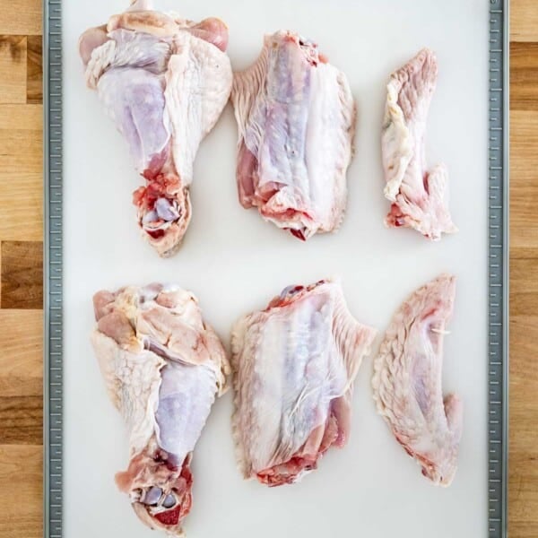 Turkey wings cut into parts on a cutting board from the top view.