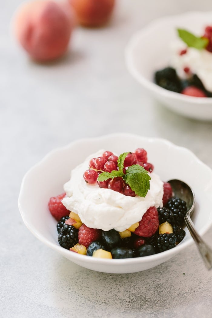 a bowl of  fruit topped off Maple Whipped Cream and fresh mint
