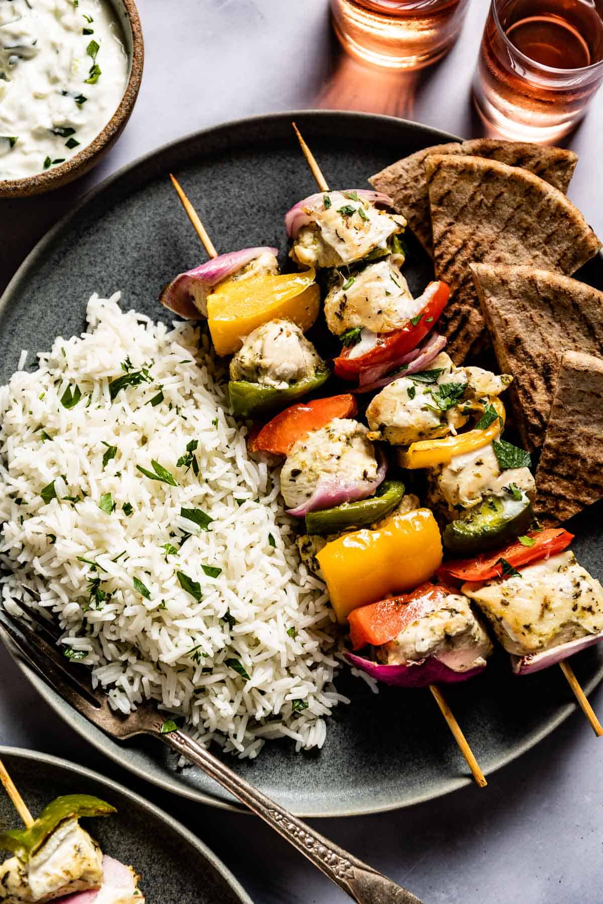 Baked chicken kabobs served with rice and pita on a plate.