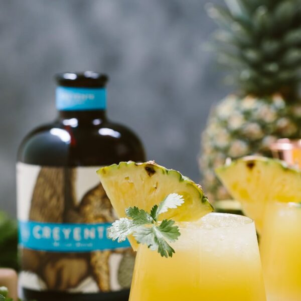 Pineapple Mezcal Cocktail garnished with a wedge of pineapple and cilantro
