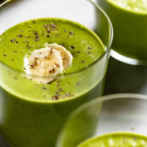 Spinach Peanut Butter Smoothie served in a glass garnished with two slices of bananas.