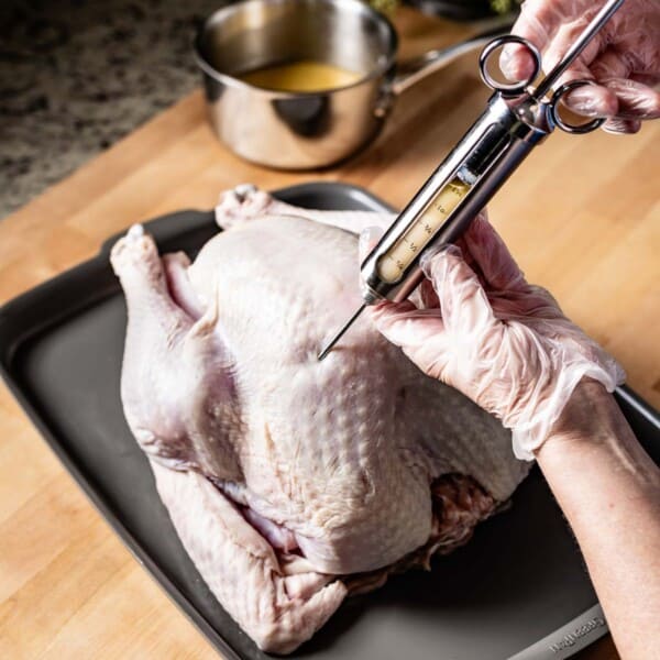 Person injecting turkey with injectable marinade using a syringe.