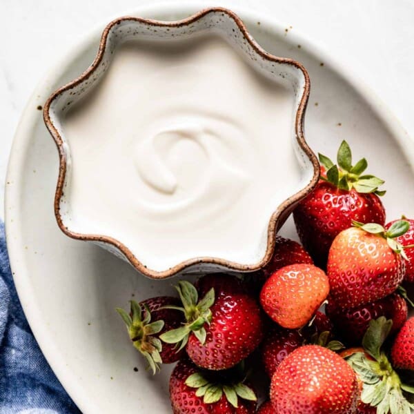 vanilla yogurt made from plain yogurt in a bowl on a plate with strawberries from top view