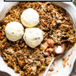Vegan Apple Crisp topped off with ice cream in a pie plate with text over it