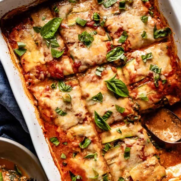 Vegetarian zucchini lasagna in a baking dish with a spoon on the side.